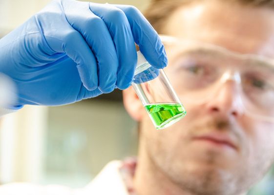 researcher holding green liquid sample