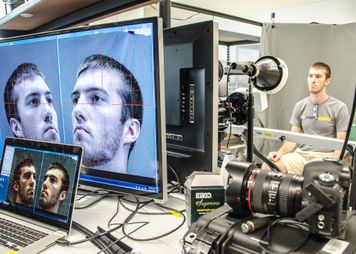 Male student being recorded, biometric images on computer screens